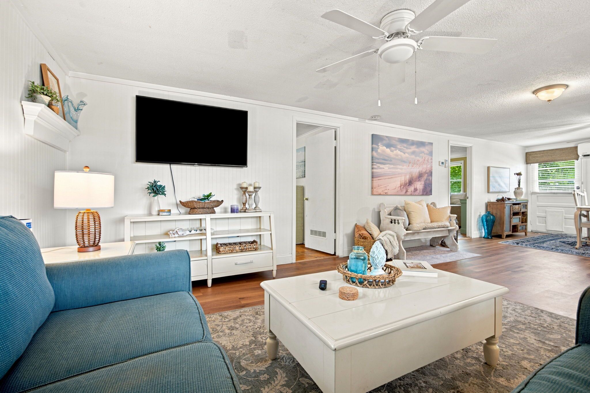 A living room with a flat-screen TV, a ceiling fan, and a dining area with a table and chairs.