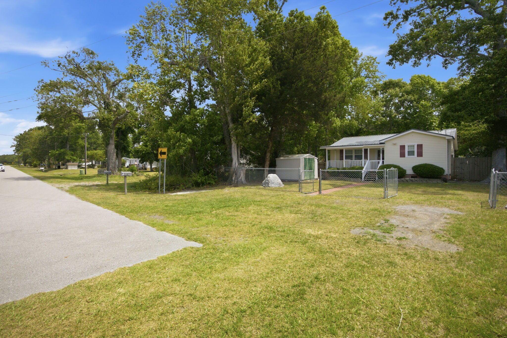A residential area with a house, a fenced yard, and a road.