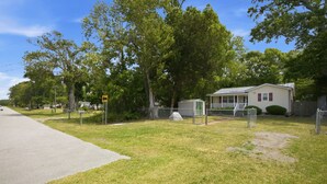 A residential area with a house, a fenced yard, and a road. - Cozy Holden Beach dog friendly beach cottage. Only 1.4 miles to Holden Beach on mainland side. (Supply)