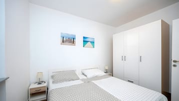 A bedroom with a bed, nightstands, a wardrobe, and two wall-mounted pictures.