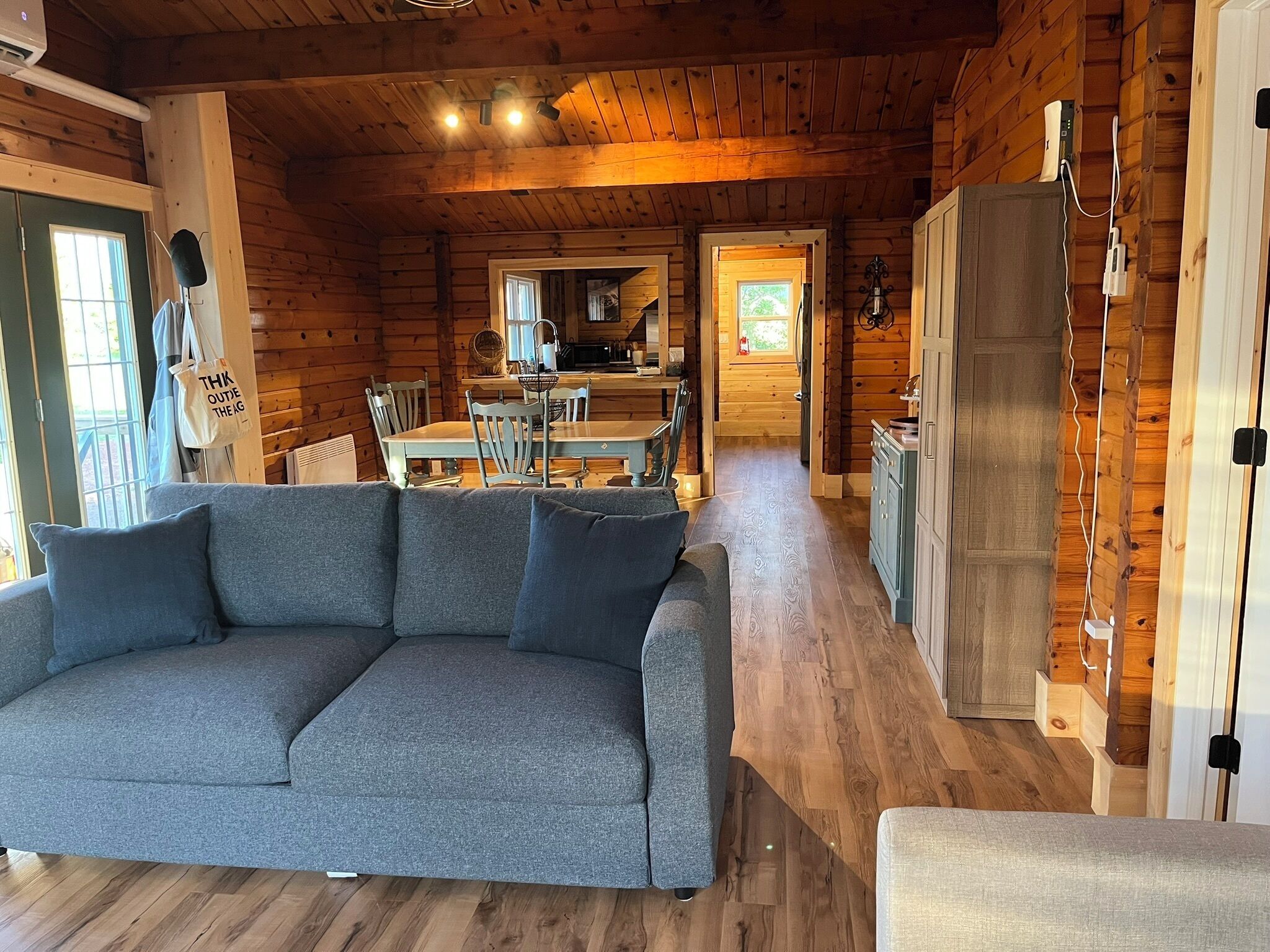 Interior acollidor d'una cabana amb sofà, taula de menjador i zona de cuina.