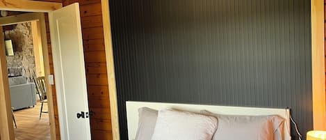 A wooden room with a bed, a nightstand, a lamp, and a ceiling fan.