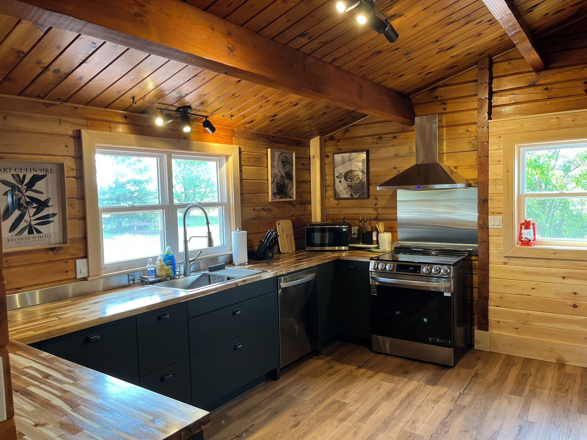 Een moderne keuken met houten wanden, een roestvrijstalen fornuis en een groot eiland met een spoelbak.