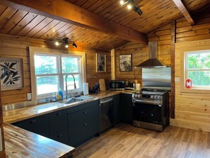 Une cuisine moderne avec des murs en bois, une cuisinière en acier inoxydable et un grand îlot central doté d’un évier.