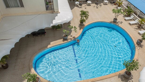 A swimming pool with a heart-shaped design, surrounded by lounge chairs and potted plants. - Mekong View Apartment and Hotel II (Phnom Penh)