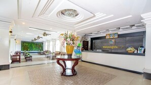 A hotel lobby with a reception desk, a large vase of flowers, and a seating area with tables and chairs. - Mekong View Apartment and Hotel II (Phnom Penh)
