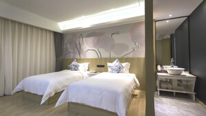 A hotel room with two beds, a bedside table, a large mirror, and a bathroom with a sink and towel rack. - Paco Hotel (Guangzhou)