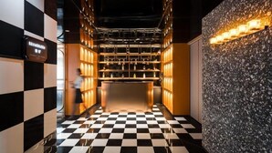A checkered floor leading to a bar area with shelves and a wall with a textured surface. - Paco Hotel (Guangzhou)