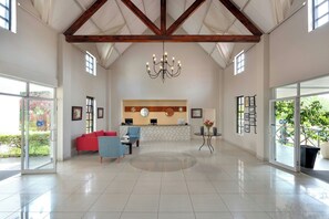 A spacious lobby with a reception desk, seating area, and large windows.