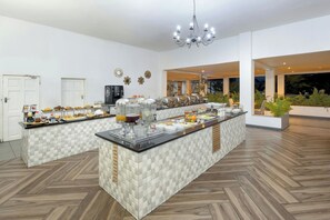 A spacious buffet area with a central island, multiple serving stations, and a chandelier.