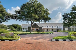A building with a paved driveway and a large tree in the foreground.