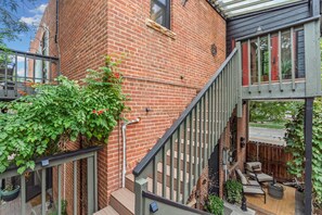 A brick building with a staircase leading to a covered outdoor area with seating. - Magnolia Market Loft | Steps to Old Town & Trails (Fort Collins)