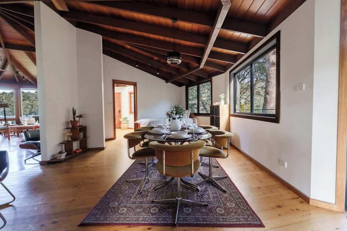 Un coin repas avec une table ronde dressée pour quatre personnes, entourée de chaises et agrémenté d’une plante au centre.