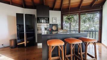 A modern kitchen with a central island, bar stools, and a view of the outdoors.