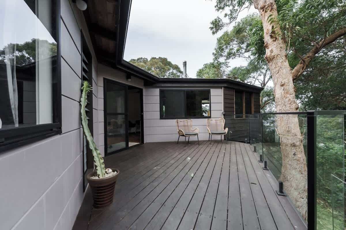 A wooden deck with chairs and a potted plant.