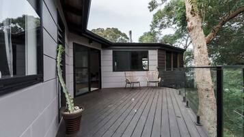 A wooden deck with chairs and a potted plant.