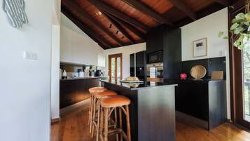 Una cocina moderna con una isla central, suelo de madera y un techo alto con vigas a la vista.