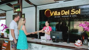 A reception desk at Villa Del Sol Beach Resort & Spa with a digital kiosk, a framed certificate, and a vase of flowers. - Villa Del Sol Beach Villas & Spa (Phan Thiet)