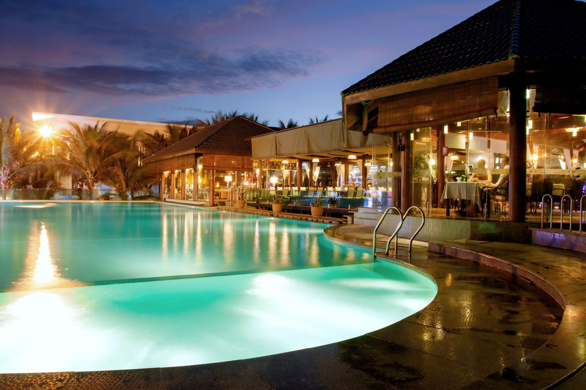 A swimming pool with a bar and seating area adjacent to it.