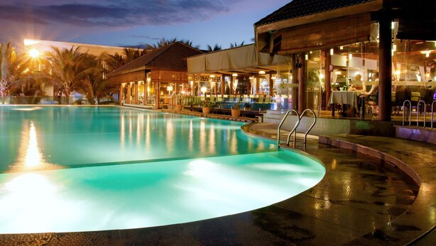 A swimming pool with a bar and seating area adjacent to it. - Villa Del Sol Beach Villas & Spa (Phan Thiet)