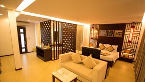 A hotel room with a sofa, a bed, a small table, and a decorative partition. - Villa Del Sol Beach Villas & Spa (Phan Thiet)