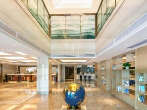 A hotel lobby with a reception desk, a globe sculpture, and a staircase leading to upper floors. - Kyriad Marvelous Hotel Shenzhen Liuyue Metro Station (Shenzhen)
