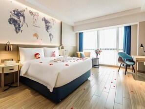 A hotel room with a large bed, a desk, a chair, a world map on the wall, and a view of the outdoors. - Kyriad Marvelous Hotel Shenzhen Liuyue Metro Station (Shenzhen)
