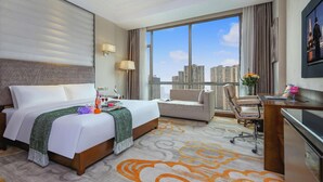 Ein Hotelzimmer mit einem großen Bett, einem Schreibtisch, einem Sessel und Blick auf die Stadt.