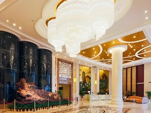 A spacious lobby with a large sculpture, a reception desk, and a seating area. - Sport Hotel (Chongqing)