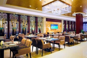 A hotel lobby with multiple dining tables and chairs, a large chandelier, and a television screen on the wall. - Sport Hotel (Chongqing)