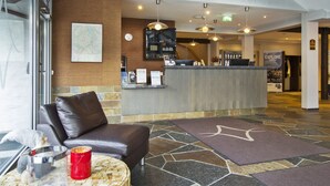 A reception area with a leather sofa, a coffee table, a map on the wall, a reception desk, and a sign for 'EXPLORE'.