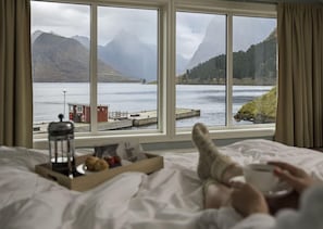 Una cama con vista a un lago y montañas.