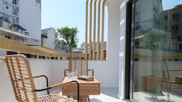 A balcony with wicker chairs, a wooden table, and a glass partition.