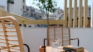 A balcony with wicker chairs, a table, and a potted plant.