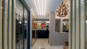 A hallway with a glass door, a chandelier, and framed artwork on the wall.