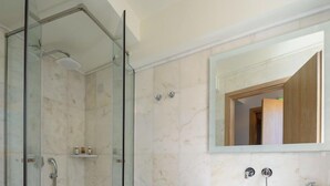 A modern bathroom with a glass-enclosed shower, a large mirror, and a white sink.
