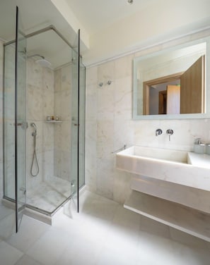 A modern bathroom with a glass-enclosed shower, a large mirror, and a white sink.