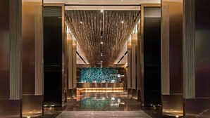 A modern lobby with a reception desk, a reflective floor, and a vertical light installation. - Paco Song Hotel Guangzhou Financial City Chepo South Metro Station (Guangzhou)