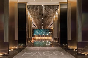 En moderne lobby med en receptionsdisk, et spejlende gulv og en lodret lyseinstallation.