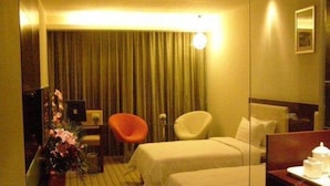 A hotel room with two beds, a desk, a chair, a mirror, and a curtain. - Wanguo International Hotel (Shenzhen)