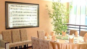 A conference room with a round table, chairs, and a large framed document on the wall. - Wanguo International Hotel (Shenzhen)