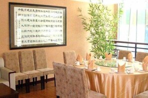 A conference room with a round table, chairs, and a large framed document on the wall. - Wanguo International Hotel (Shenzhen)