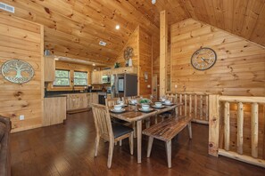 A wooden cabin interior with a dining area, kitchen, and a clock on the wall. - Welcome to Sleepy Bear, a spacious three-bedroom, three-full-bath with a Swim Sp (Sevierville)
