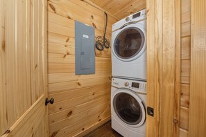 A compact laundry room with two stacked washing machines and a utility box on the wall. - Welcome to Sleepy Bear, a spacious three-bedroom, three-full-bath with a Swim Sp (Sevierville)