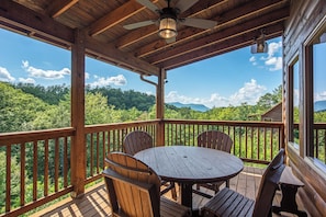 A wooden deck with a round table and chairs, overlooking a forested landscape. - Welcome to Sleepy Bear, a spacious three-bedroom, three-full-bath with a Swim Sp (Sevierville)