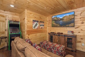 A cozy room with a wooden interior, a sofa, a small table, a snack bar, and a large window with a view of a river. - Welcome to Sleepy Bear, a spacious three-bedroom, three-full-bath with a Swim Sp (Sevierville)