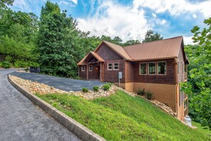 A log cabin with a pitched roof, a front porch, and a stone foundation. - Welcome to Sleepy Bear, a spacious three-bedroom, three-full-bath with a Swim Sp (Sevierville)