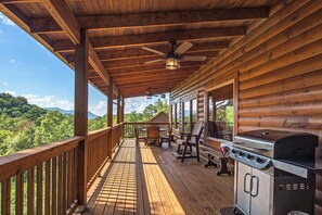 A wooden deck with a grill and seating, overlooking a forested area. - Welcome to Sleepy Bear, a spacious three-bedroom, three-full-bath with a Swim Sp (Sevierville)