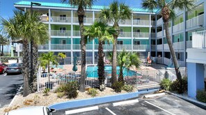 A multi-story hotel with a pool area, palm trees, and a parking lot. - Pelican Pointe  213:Walk to Beach~Pool~Free Parking (Clearwater Beach)