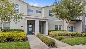 A modern two-story residential building with a covered entrance, a number '800' sign, and well-maintained landscaping. - Pebble Beach Retreat (Kissimmee)
